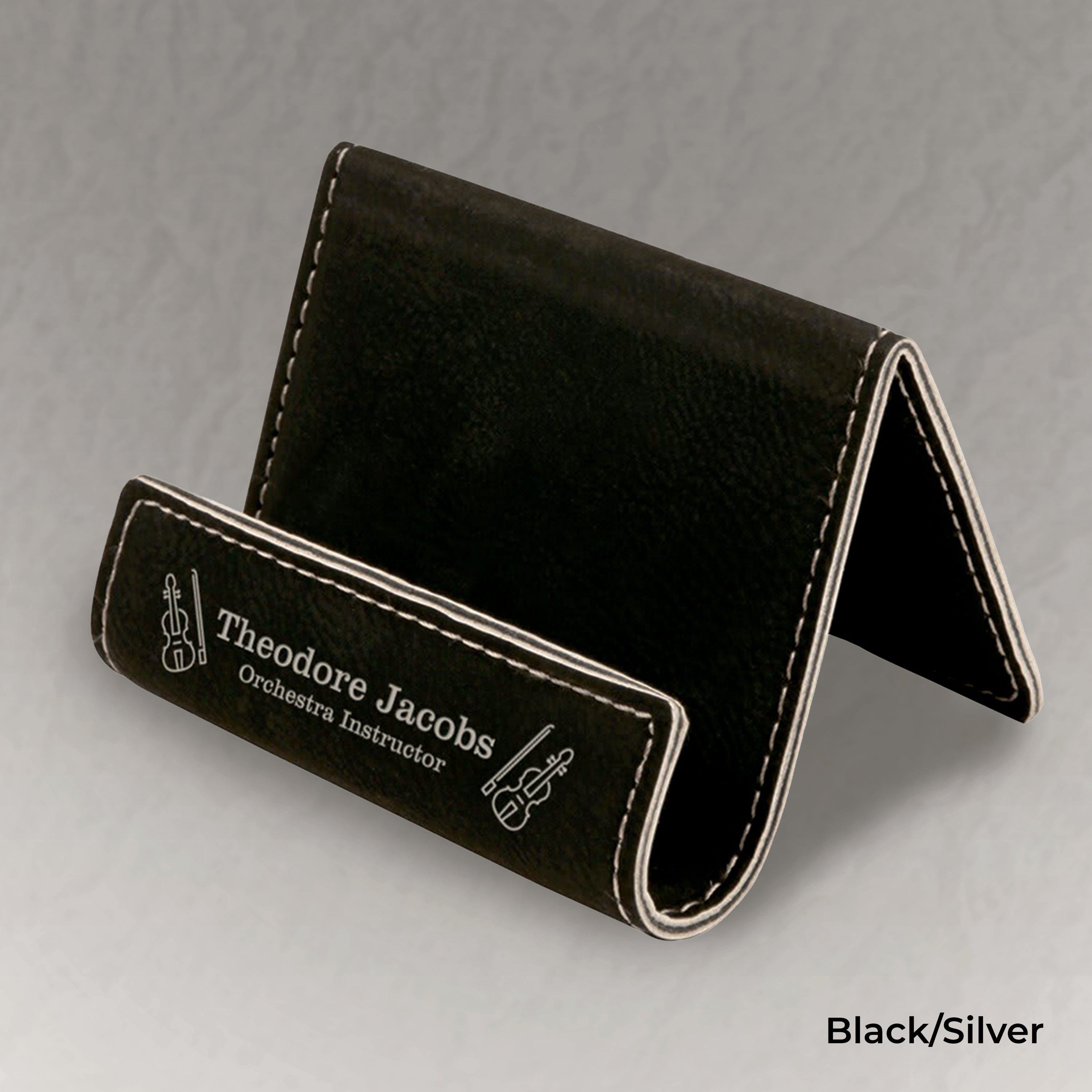 Black business card holder with engraved text on a gray background