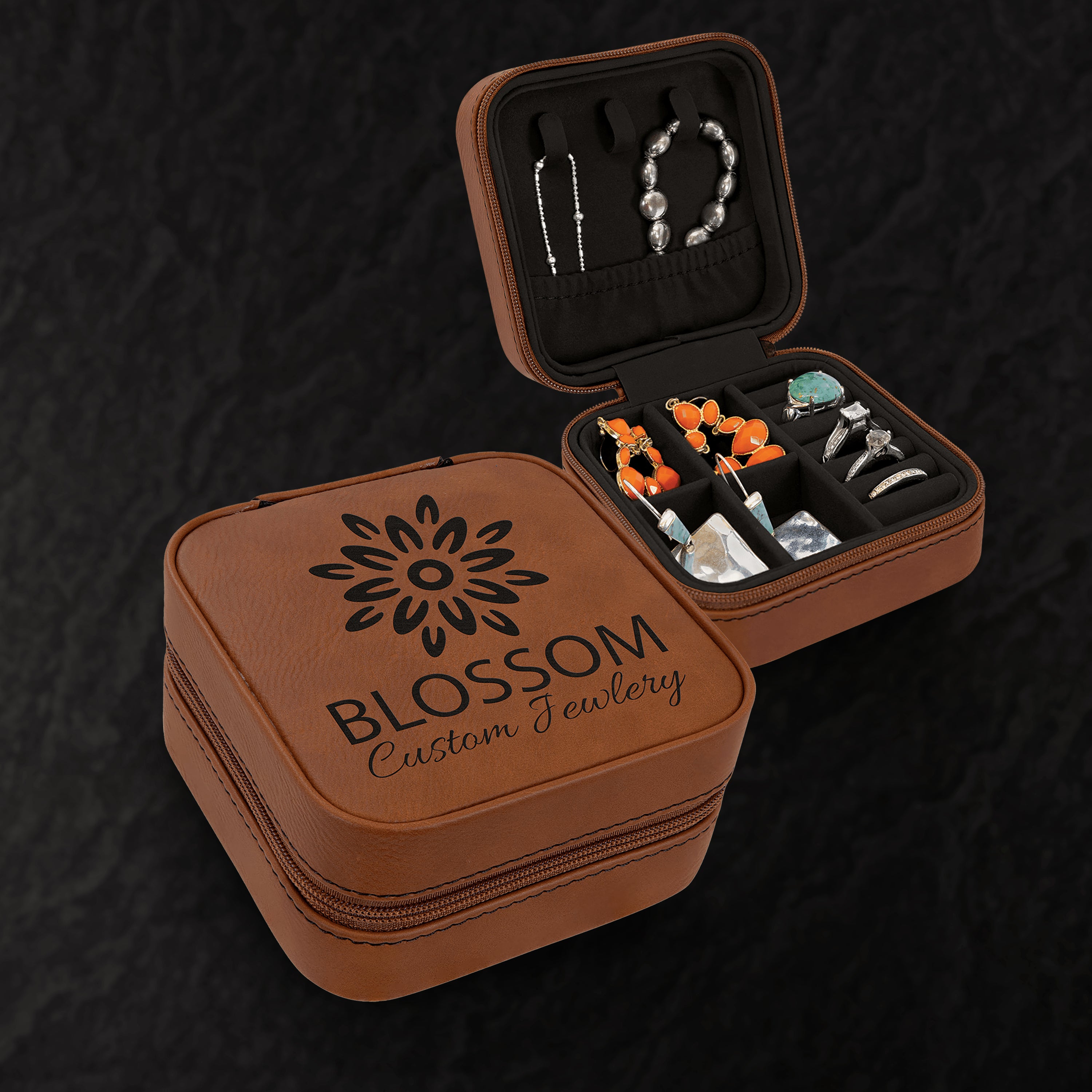 Brown jewelry case with 'Blossom Custom Jewelry' logo, containing jewelry on a dark background