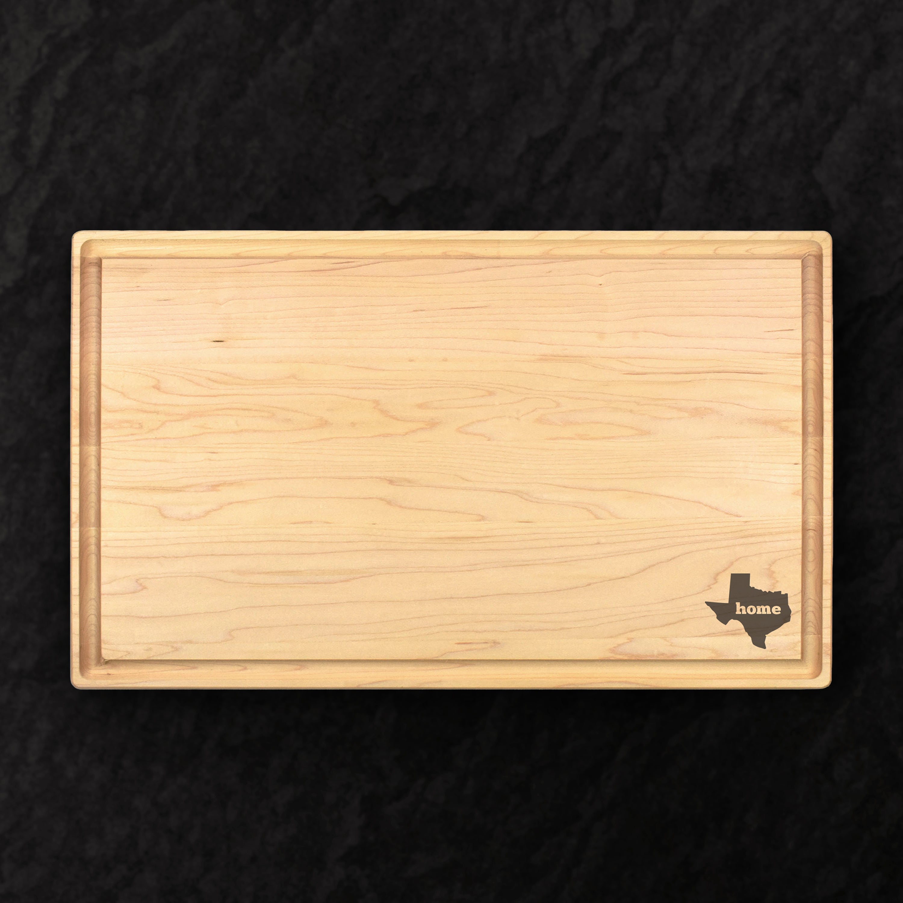 Wooden cutting board with Texas shape and 'home' text on a black background
