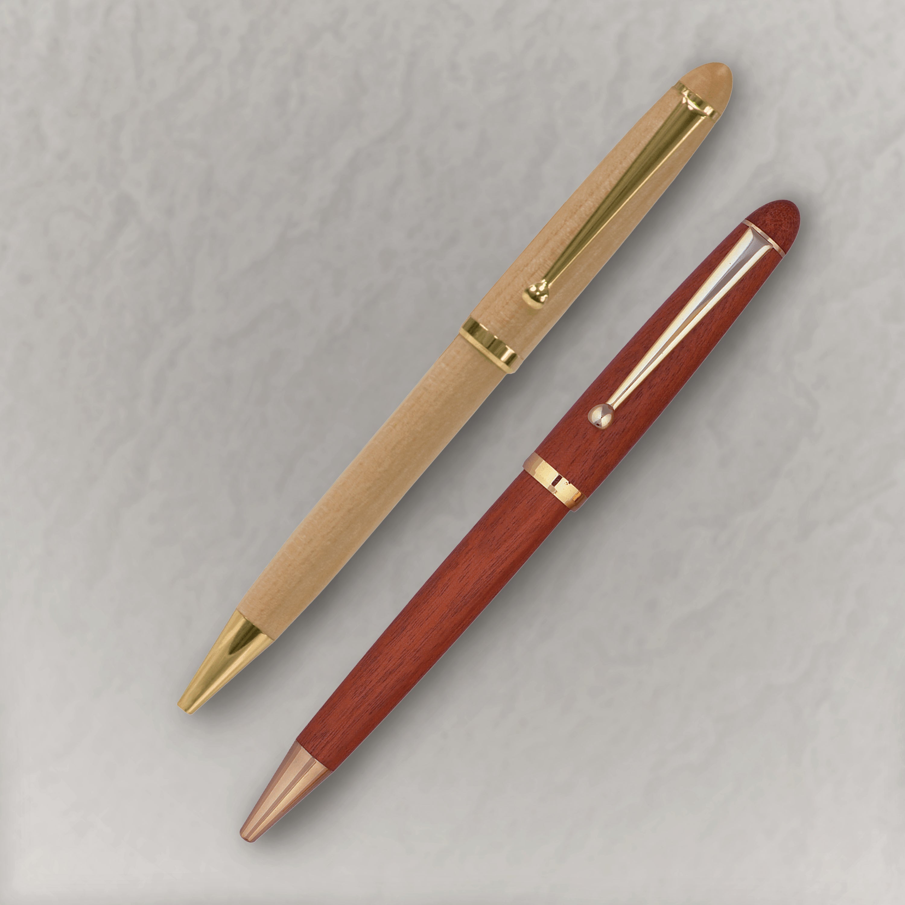 Two pens, one gold and one red, on a light gray background