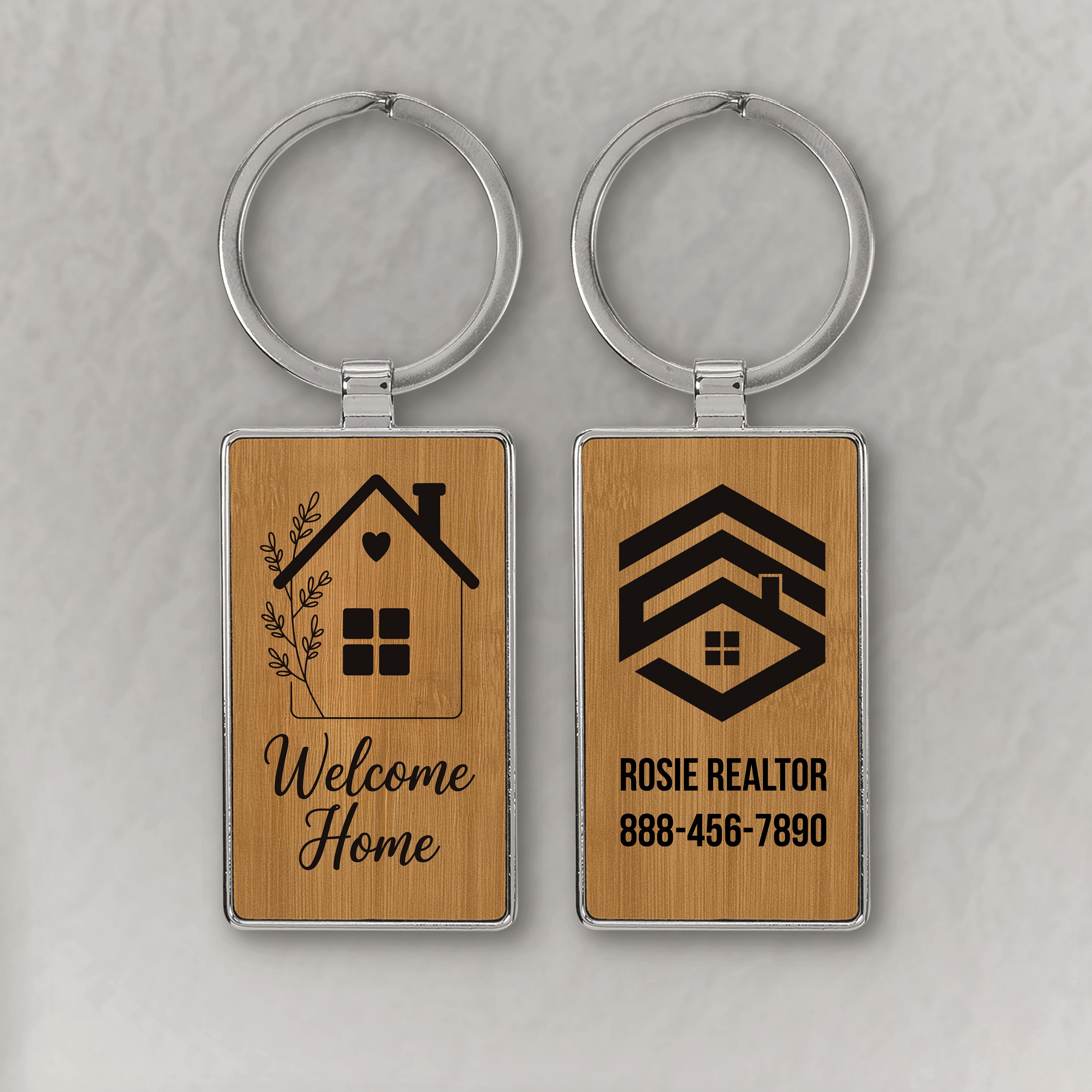 Two wooden keychains with Welcome Home and Realtor logo on a gray background
