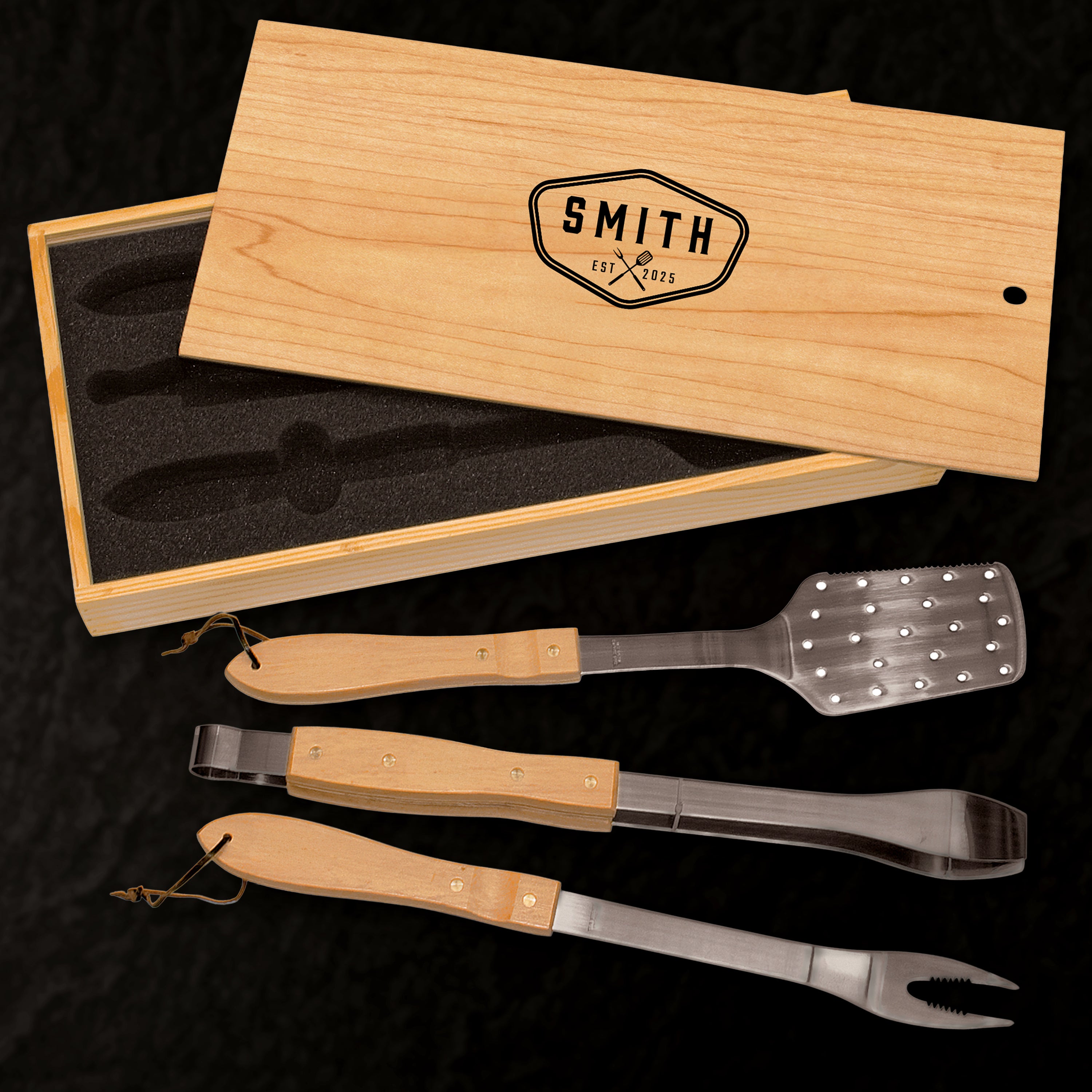 Set of barbecue tools with wooden handles in a branded box on a dark background