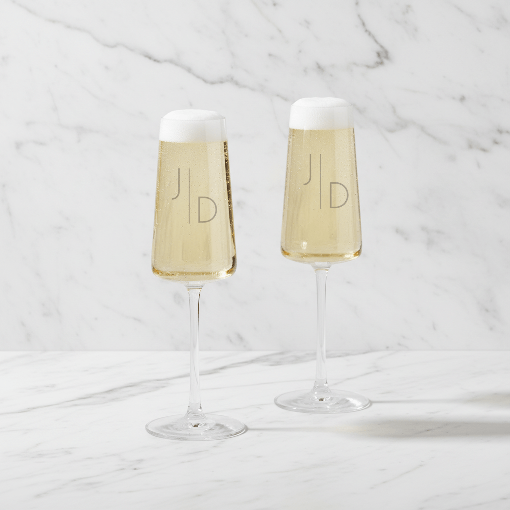 Two champagne flutes with white wine on a marble surface