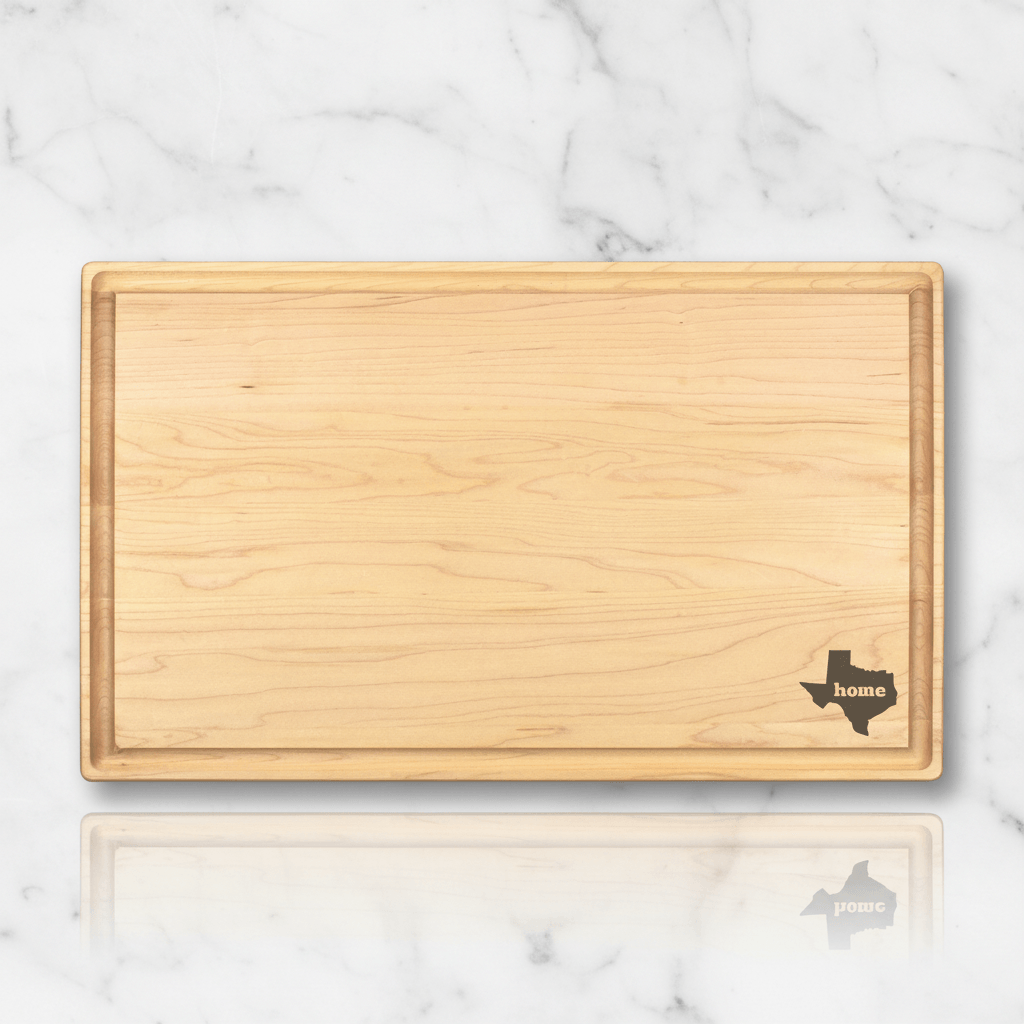Wooden cutting board with Texas shape and 'home' text on a marble surface