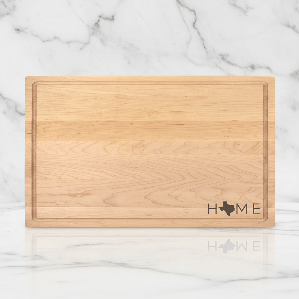 Wooden cutting board with 'HOME' and a map of Texas engraving on a marble background