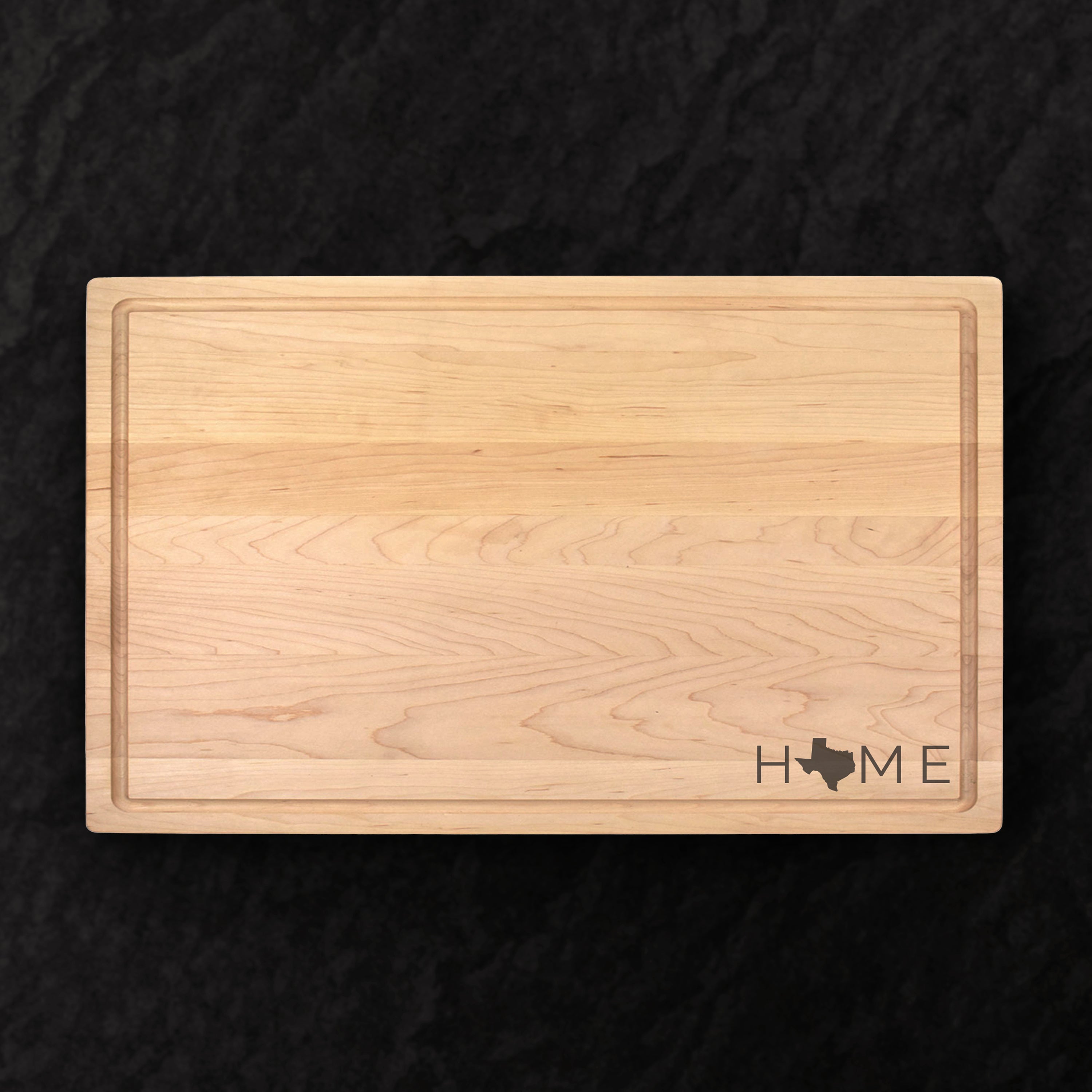 Wooden cutting board with 'HOME' and a state outline on a black background