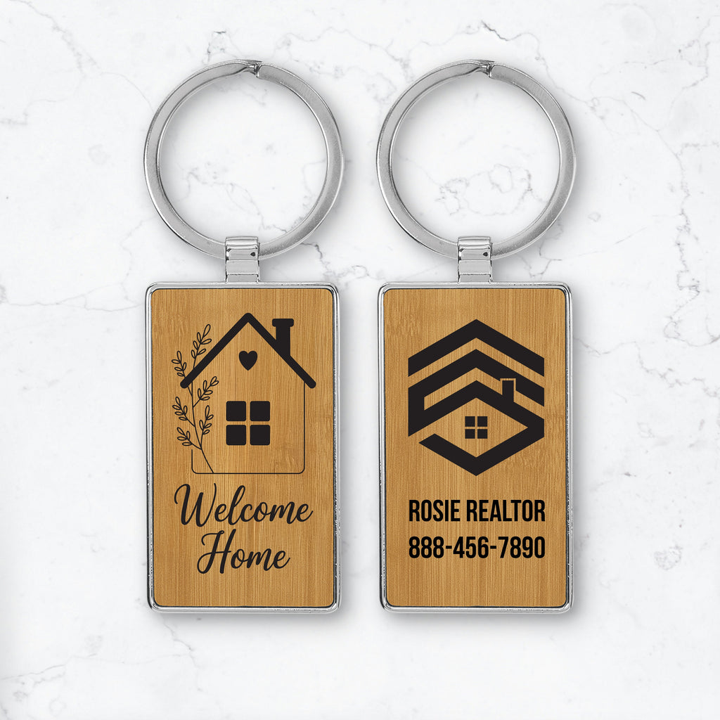 Two wooden keychains with engraved designs and text on a light marble background.