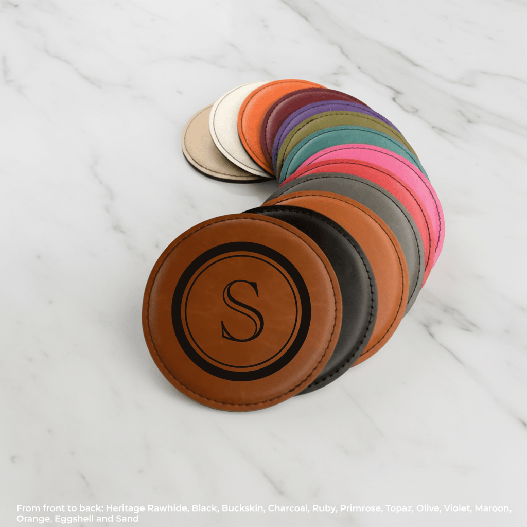 Set of round leather coasters with a letter 'S' in the center, arranged in a circular pattern on a white marble surface.