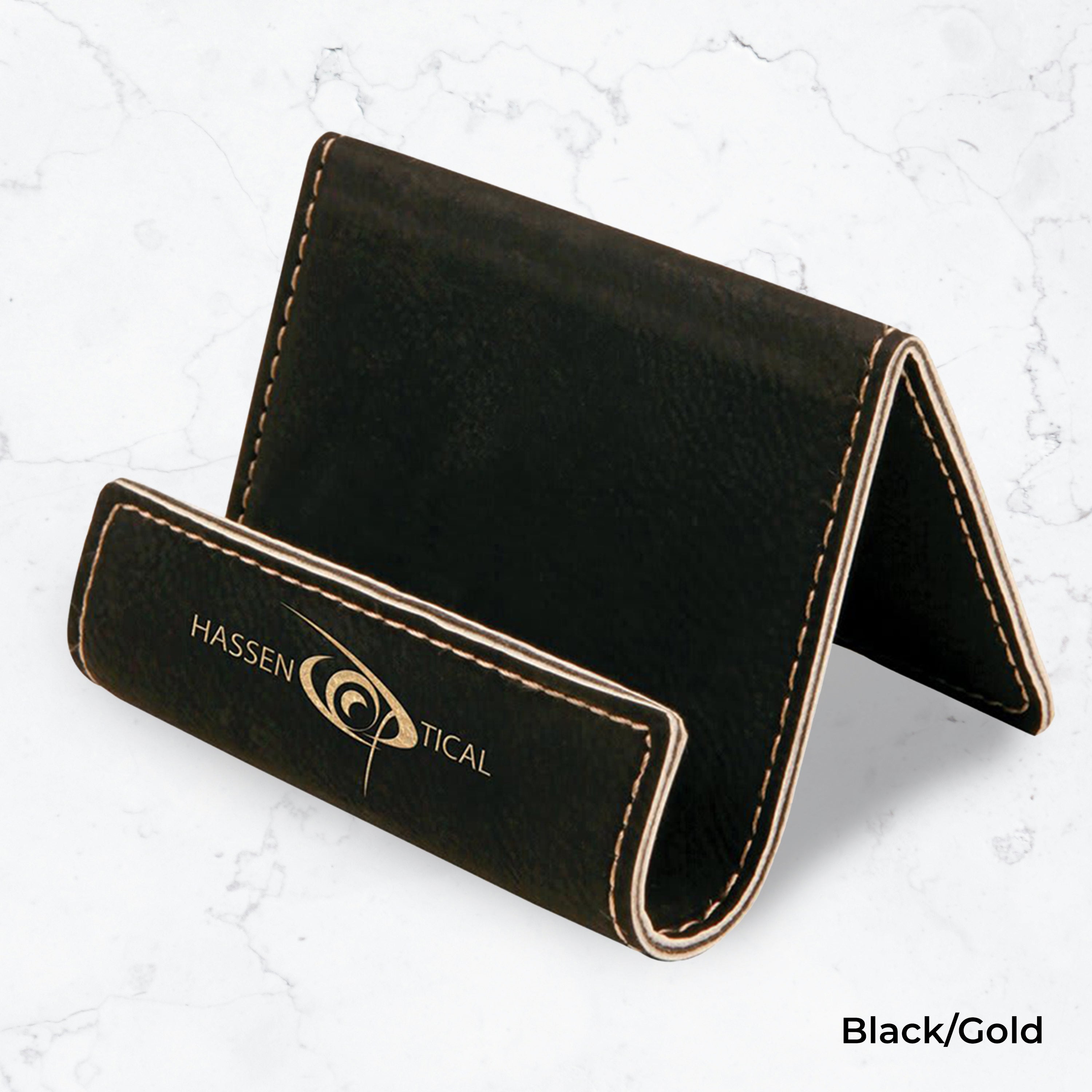 Black business card holder with gold engraving on a marble background