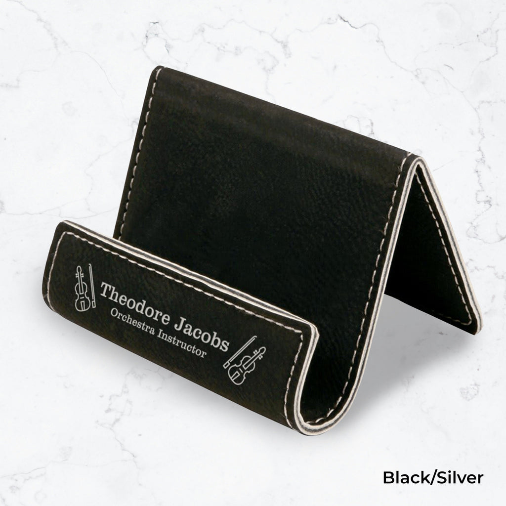 Black business card holder with silver engraving on a marble background