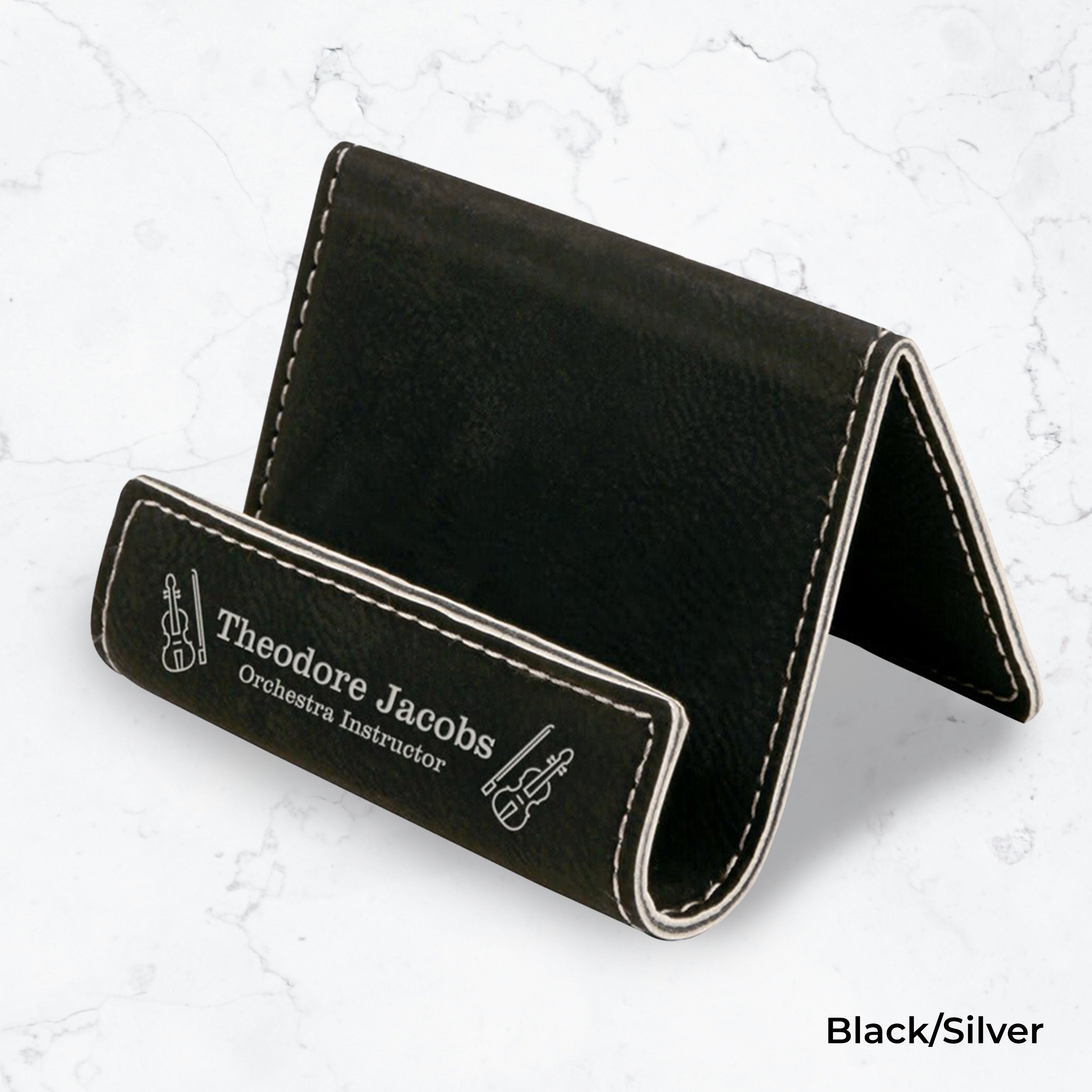 Black business card holder with silver engraving on a marble background