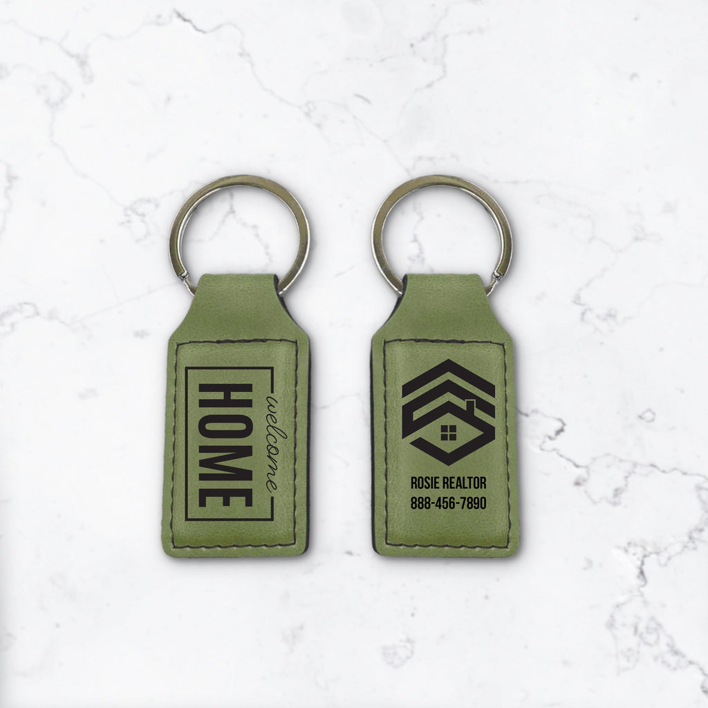 Two green keychains with engraving on a white marble background