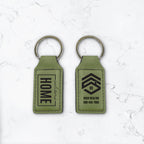 Two green keychains with engraving on a white marble background