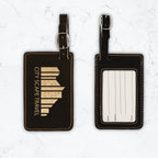 Black luggage tags with gold engraving on white marble background