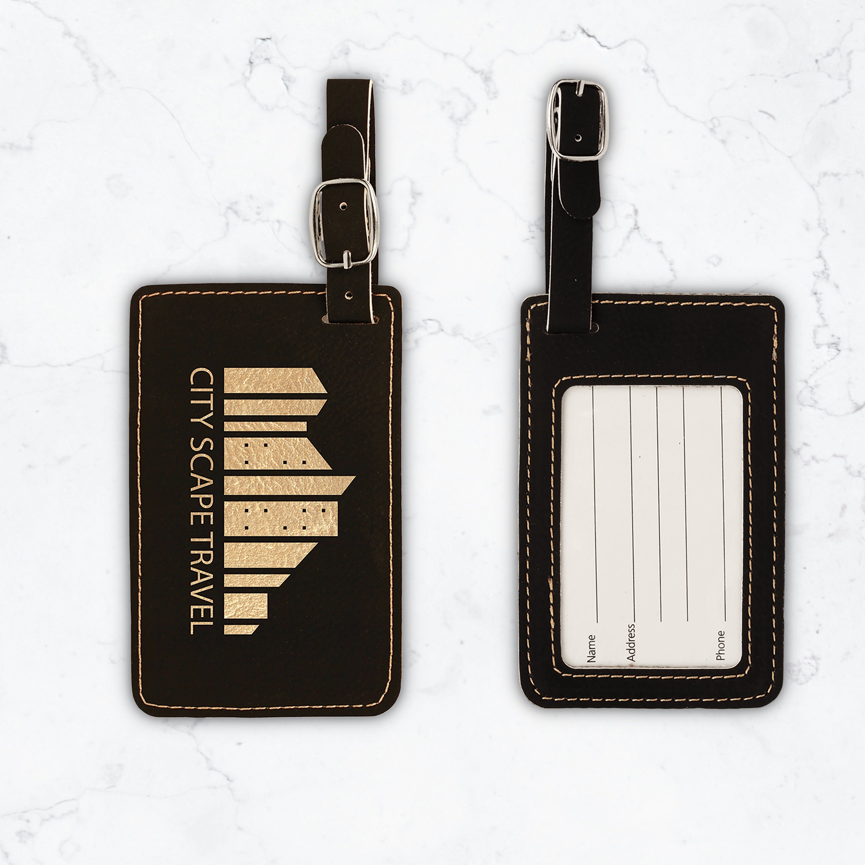 Black luggage tags with gold engraving on white marble background