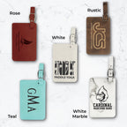 Five luggage tags in different colors and engravings on a white marble background.