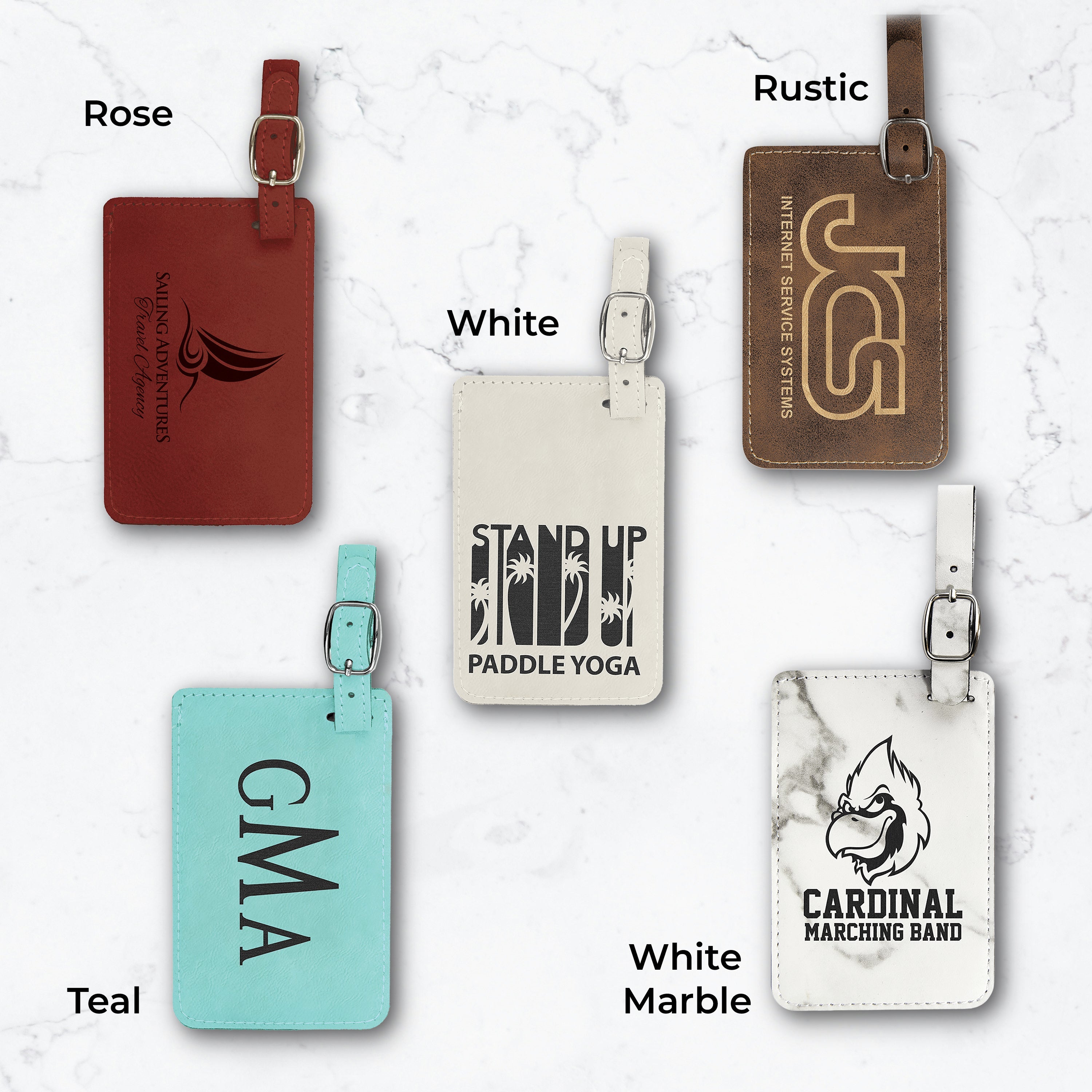 Five luggage tags in different colors and engravings on a white marble background.