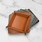 Set of square leather trays in various colors on a marble surface