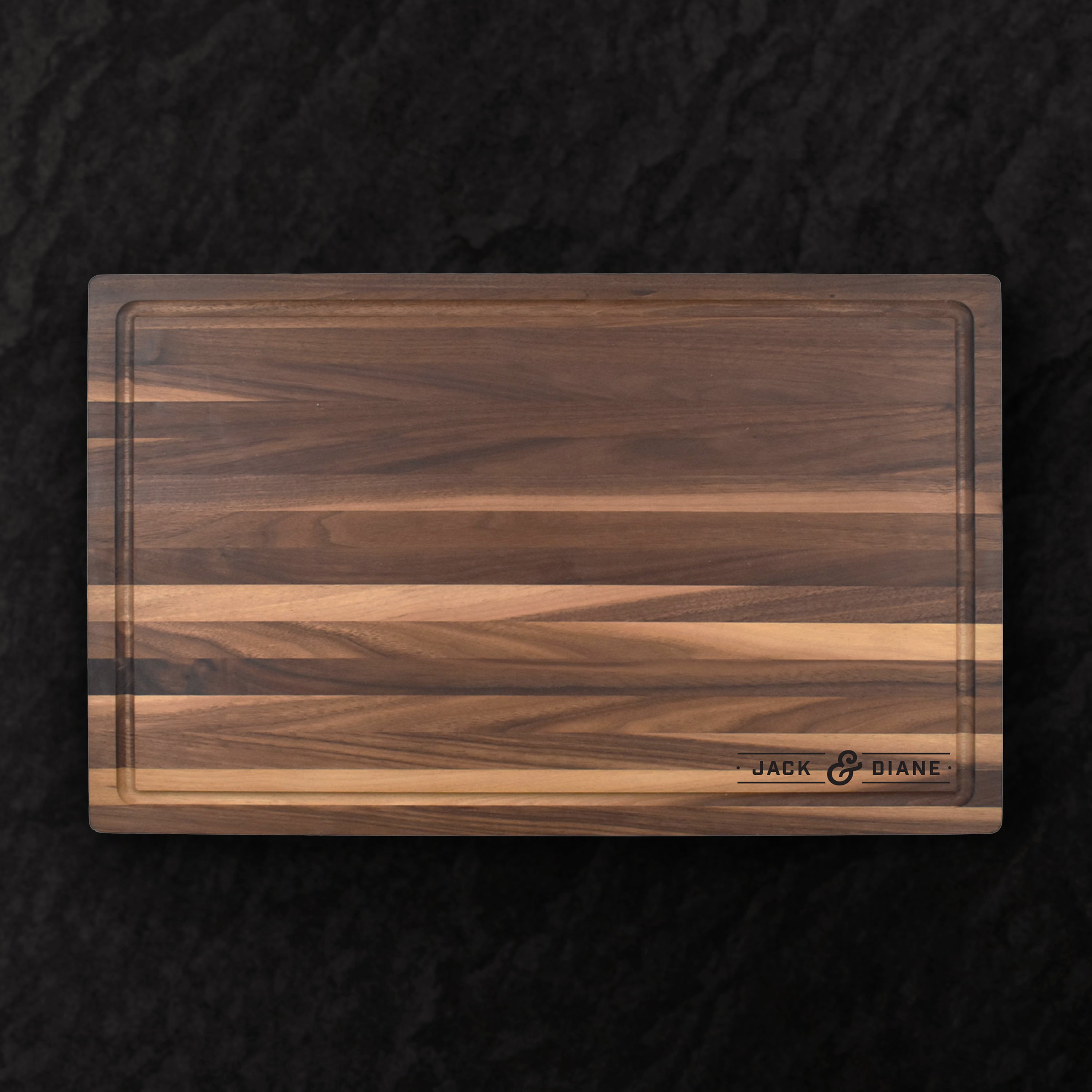 Wooden cutting board with a dark brown and light brown striped pattern on a black background