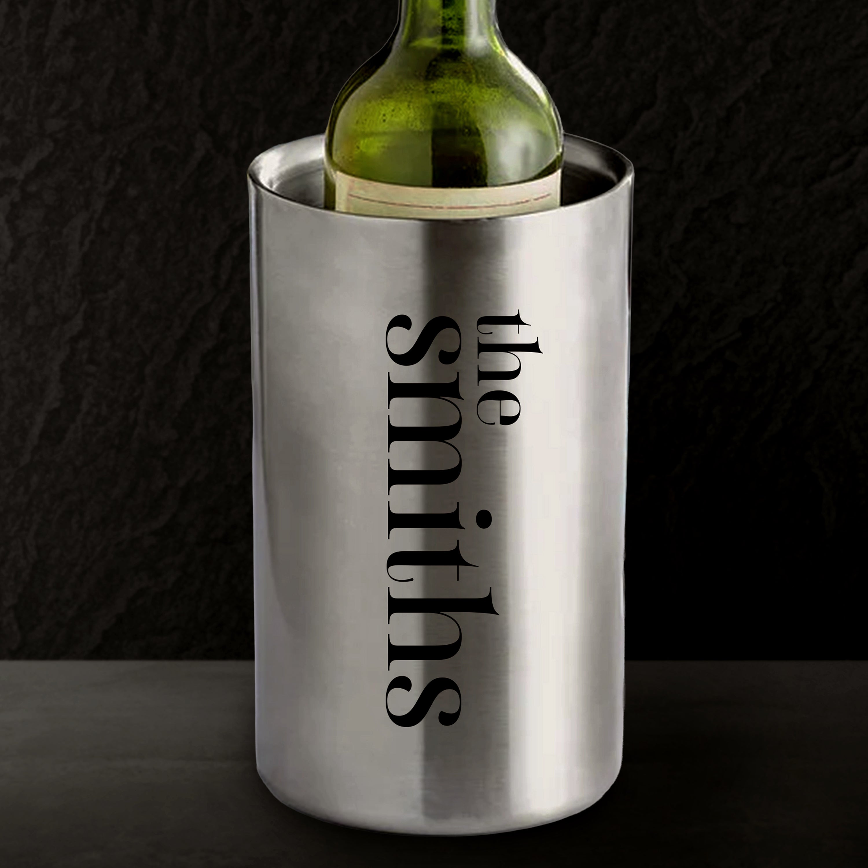 Stainless steel wine cooler with 'the smiths' engraving holding a green wine bottle against a black background.