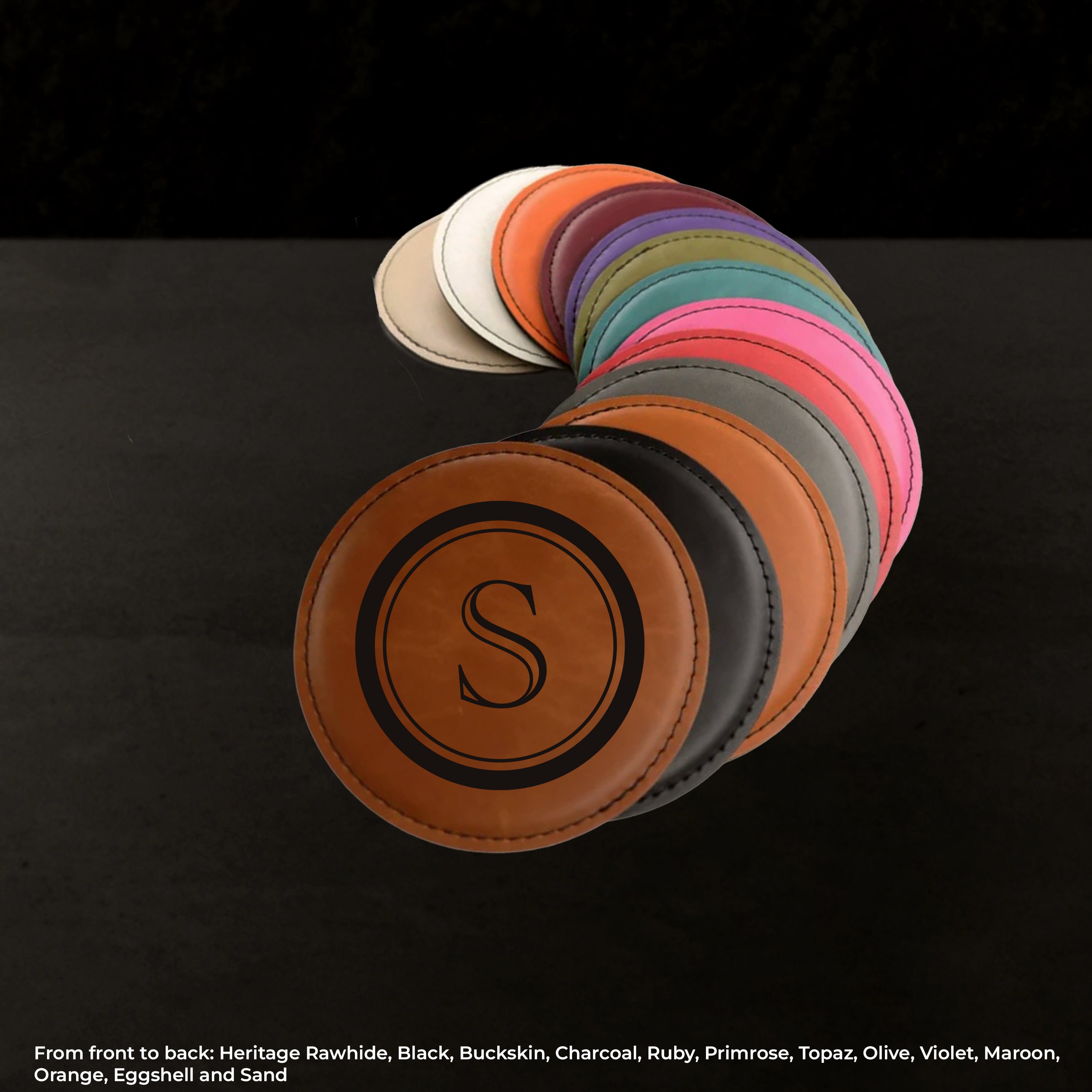 Set of leather coasters in various colors arranged in a curved row on a black background.