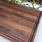 Wooden cutting board with 'The Chapman Family' engraving on a white surface.